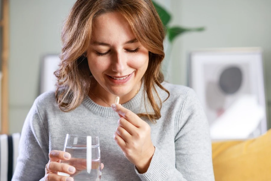 Woman taking a pill with a glass of water.